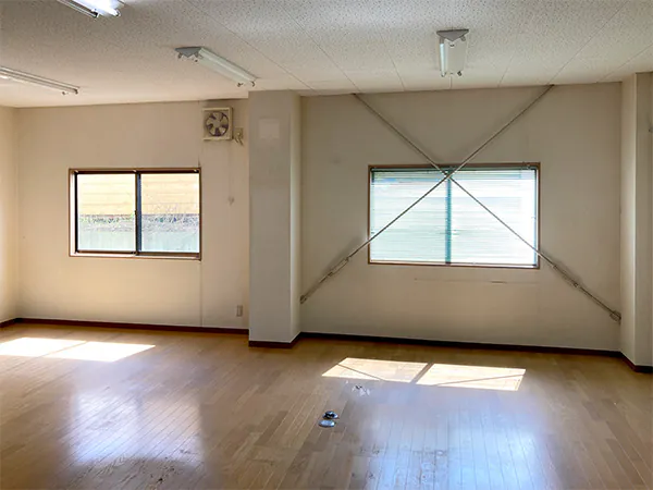 のリフォーム施工前、広いオフィスフロアのフローリングと窓